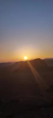 a sunset in the desert with the sun in the sky at Wadi rum safari 1 camp in Wadi Rum