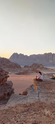 a person sitting on a rock in the desert at Wadi rum safari 1 camp in Wadi Rum