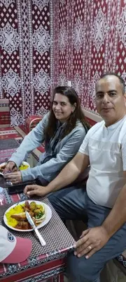 a man and woman sitting at a table with a plate of food at Wadi rum safari 1 camp in Wadi Rum
