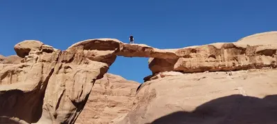 a man standing on top of a rock formation at Wadi rum safari 1 camp in Wadi Rum