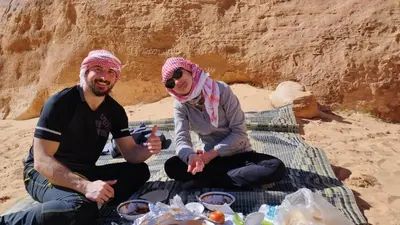 a man and a woman sitting on a blanket on the beach at Wadi rum safari 1 camp in Wadi Rum