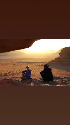 two people sitting on the beach looking at the ocean at Wadi rum sand Delight camp in Wadi Rum