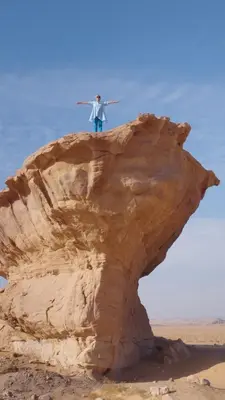 a man standing on top of a rock in the desert at Wadi rum sand Delight camp in Wadi Rum