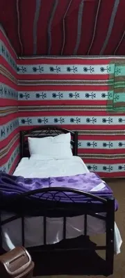 a bed in a room with a red and white wall at Wadi rum sand Delight camp in Wadi Rum