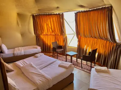 a room with three beds and chairs and a window at Arjowana Luxury Camp & Bubbles Hotel in Wadi Rum