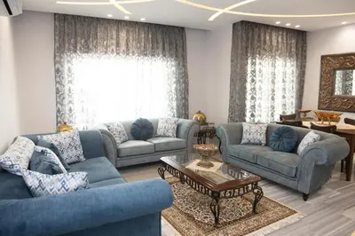 a living room with two blue couches and a table at Hanan Residence 01 - 3BR, Der Ghbar 165m2 in Amman