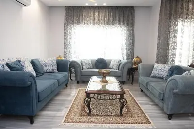 a living room with blue couches and a table at Hanan Residence 01 - 3BR, Der Ghbar 165m2 in Amman