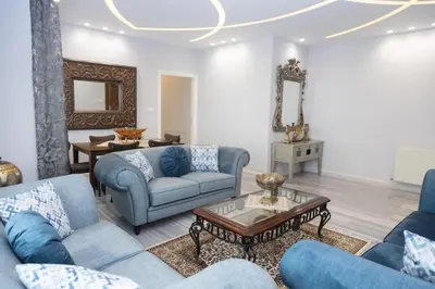 a living room with blue couches and a table at Hanan Residence 01 - 3BR, Der Ghbar 165m2 in Amman