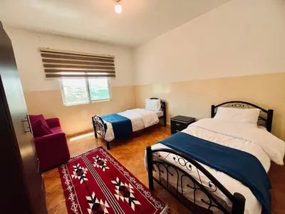 a bedroom with two beds and a red couch at Petra Gold Inn Apartments in Wadi Musa