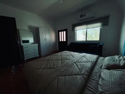 a bedroom with a bed and a dresser and a window at Petra Gold Inn Apartments in Wadi Musa