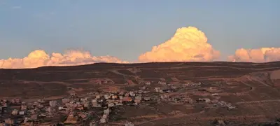 a group of buildings on a hill with clouds in the sky at Leen Guest House in Wadi Musa