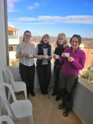 four women standing on a balcony with cups of coffee at Leen Guest House in Wadi Musa