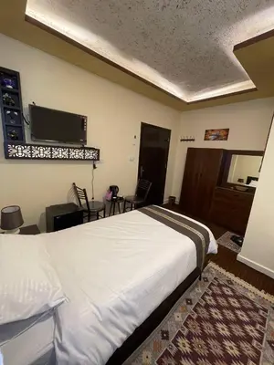 a bedroom with a bed and a flat screen tv at Ad Deir Guesthouse in Wadi Musa