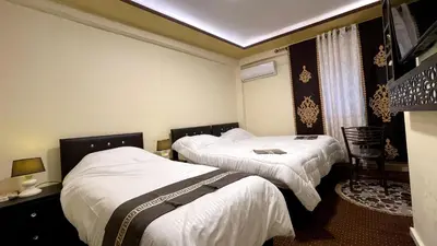 a hotel room with two beds with white sheets at Ad Deir Guesthouse in Wadi Musa