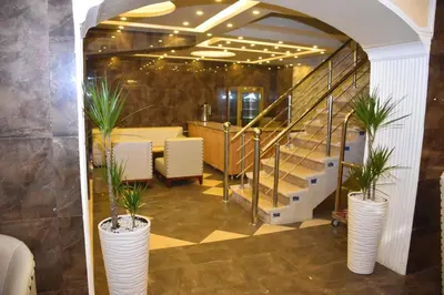 a lobby with stairs and plants in white vases at Madison Hotel in Amman