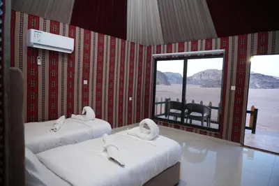 two beds in a room with a view of the desert at Shaheen Camp Wadi rum in Wadi Rum