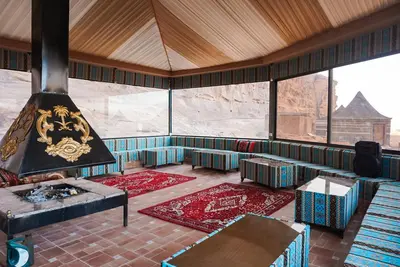 a room with a fireplace and a couch and tables at Shaheen Camp Wadi rum in Wadi Rum