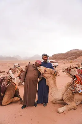 two men standing in the desert with their camels at Shaheen Camp Wadi rum in Wadi Rum