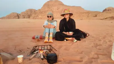 two women sitting next to a fire in the desert at Youssef camp Wadi Rum in Wadi Rum