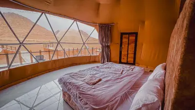 a bed in a room with a large window at Mahmmad Luxury Camp in Wadi Rum