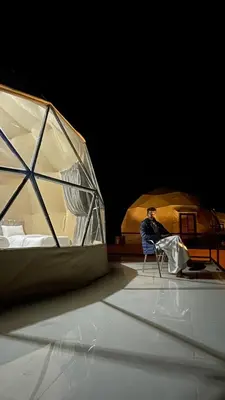 a man sitting in a chair in front of a tent at Mahmmad Luxury Camp in Wadi Rum