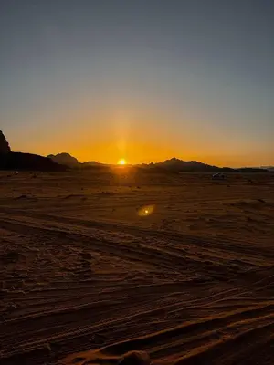a sunset in the desert with the sun setting at Scoop Rum in Wadi Rum