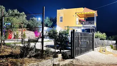 a fence in front of a yellow house at Alreem Farm in Ajloun