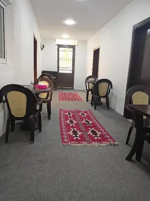 a room with tables and chairs and a red rug at Grandpa House in Wadi Musa