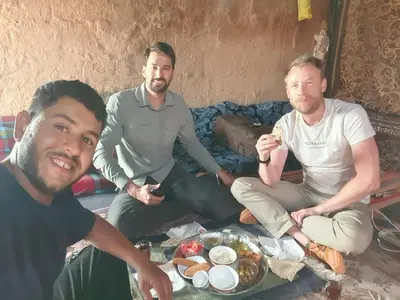 a group of three men sitting on a couch with food at Bedouin experiences in Aqaba