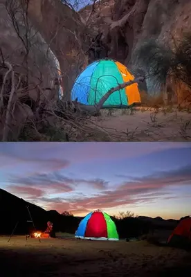 a tent is lit up at night and a person sitting in front at Wadi rum Wild life camp in Wadi Rum