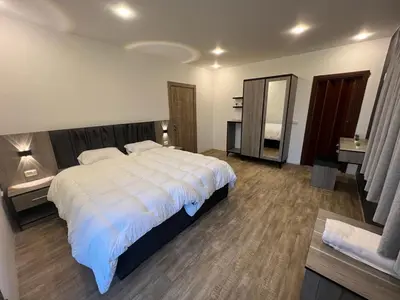 a bedroom with a large white bed and a mirror at Caprios motel in Al Qasţal
