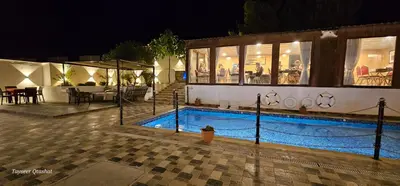 a swimming pool in front of a building at night at Al Namteh Lodge in ‘Ābil