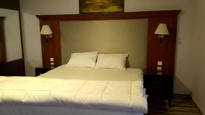 a bedroom with a bed with white sheets and two lamps at Al Namteh Lodge in ‘Ābil