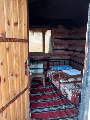 a small room with two beds and a window at Feynan wild camp in Al Khuraybah