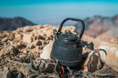 a black tea kettle sitting on a pile of rocks at Feynan wild camp in Al Khuraybah