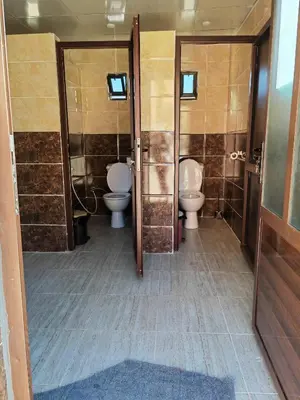 a bathroom with two toilets and two sinks at Namla Bedouin Camp in Umm Şawwānah