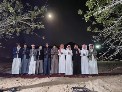 a group of women posing for a picture at night at Namla Bedouin Camp in Umm Şawwānah