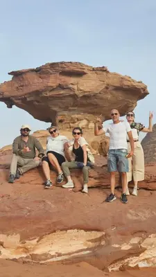 a group of people sitting on a rock formation at Rum Darien Camp in Wadi Rum