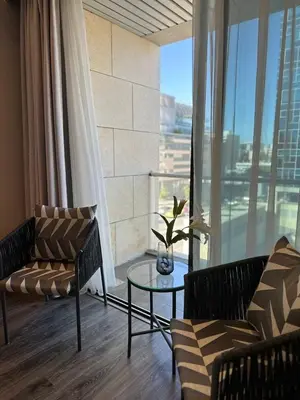 a living room with a table and chairs and a large window at Downtown pearl Amman in Amman