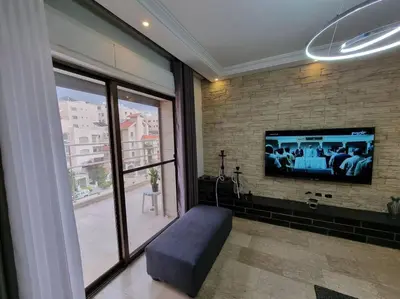 a living room with a tv on a brick wall at Deir Ghbar 3 rooms apart in Amman
