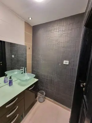 a bathroom with two sinks and a black tiled wall at Deir Ghbar 3 rooms apart in Amman
