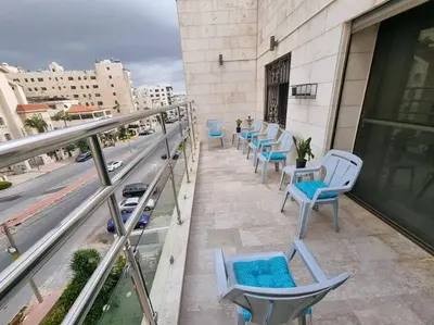 a row of chairs on the balcony of a building at Deir Ghbar 3 rooms apart in Amman