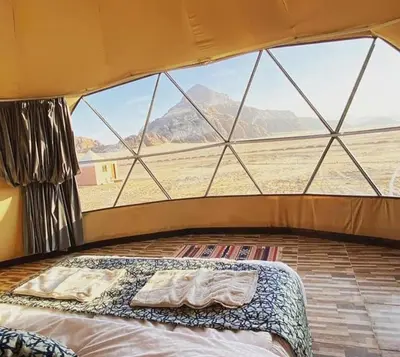 a bed in a tent with a view of the desert at Wade rum natural in Wadi Rum