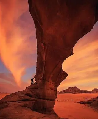 a person standing on a rock in the desert at Wade rum natural in Wadi Rum