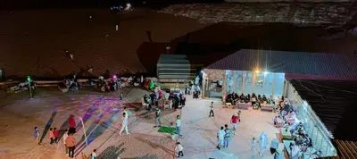 a group of people standing around a stage at night at blueskyrum. in Wadi Rum