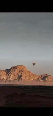 a parachute is flying over a desert with a mountain at Natalie Wadi Rum camp in Wadi Rum