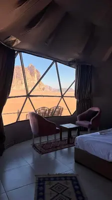 a bedroom with a large window with chairs and a bed at Natalie Wadi Rum camp in Wadi Rum