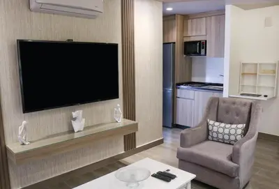 a living room with a television and a chair at Red Carpet Hotel & Suites in Amman
