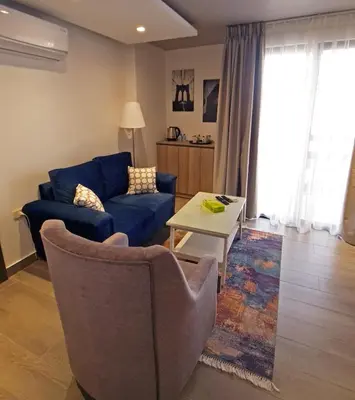 a living room with a blue couch and a table at Red Carpet Hotel & Suites in Amman