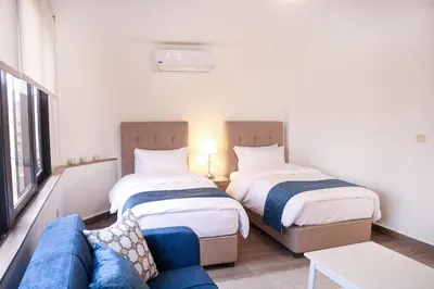 two beds in a small room with a couch at Red Carpet Hotel & Suites in Amman